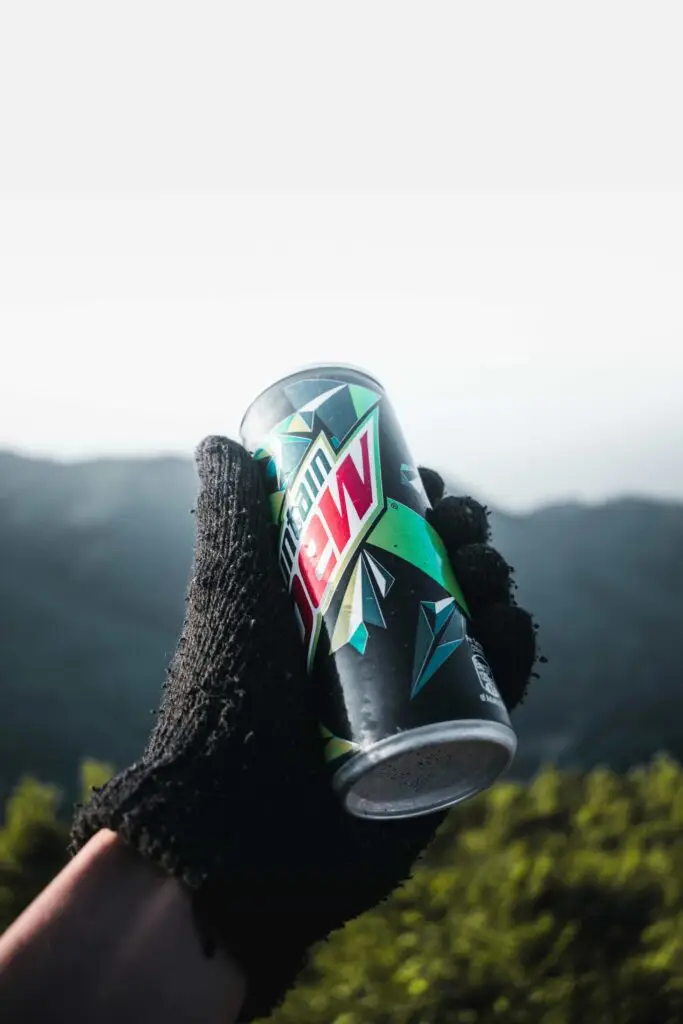 Mountain Dew vs. Coke: Which is Worse For Your Teeth? 1 hand holding a can of mountain dew
